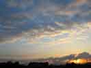 【サムネイル】 太陽が雲と家並みの隙間から昇ってくる写真